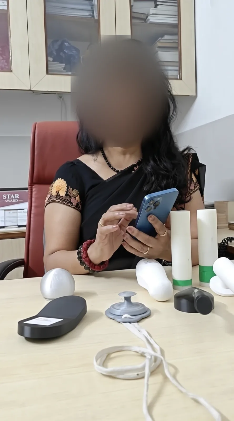 A doctor holding a phone and talking through the prototype, with the physical forms on the desk, face blurred