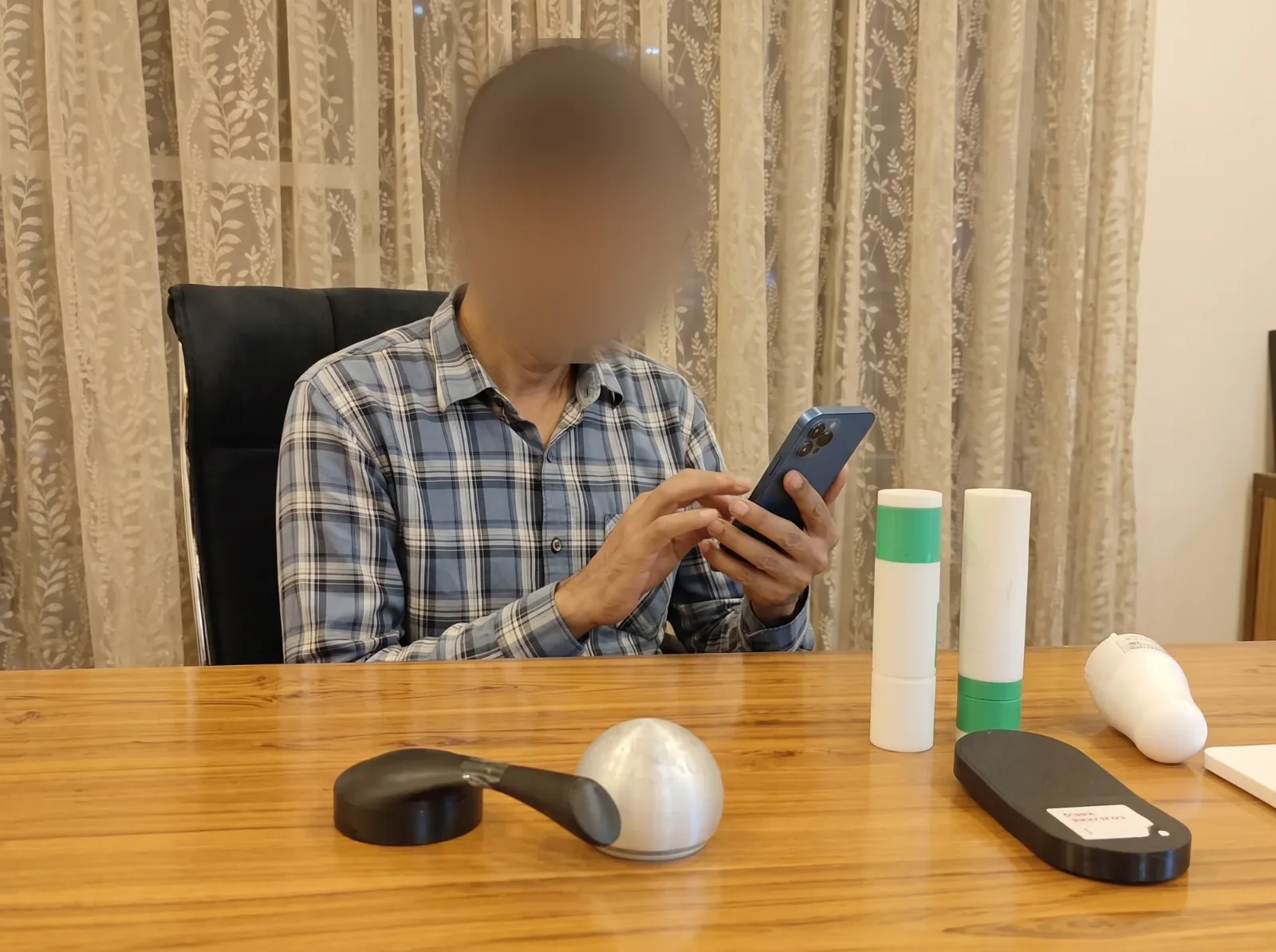 A doctor at a desk tapping through the prototype on a phone, with the physical forms in front of him, face blurred